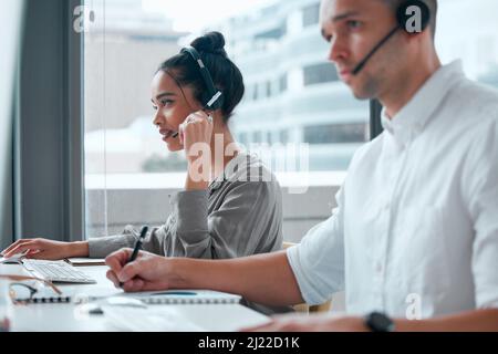 We are the dream team. Shot of two young businesspeople working together in a call center. Stock Photo