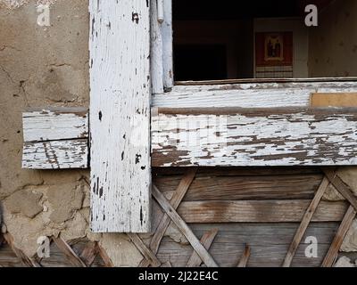 The windows of an old abandoned house with broken glass. An empty building with no doors or windows. The concept of demolition or collapse of a buildi Stock Photo