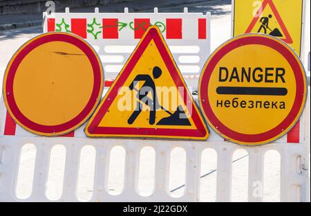 Road works sign hanging on a fence close up. Stock Photo