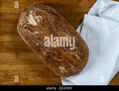 whole grain wheat bread made with sour dough on wooden surface with white cloth shot from above Stock Photo