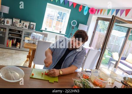 Man in the kitchen, chopping carrots and preparing vegetables Stock Photo