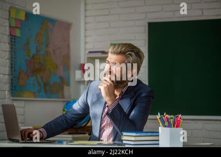 Portrait of confident male teacher in classroom. Teacher smiling at classroom at the elementary school Stock Photo