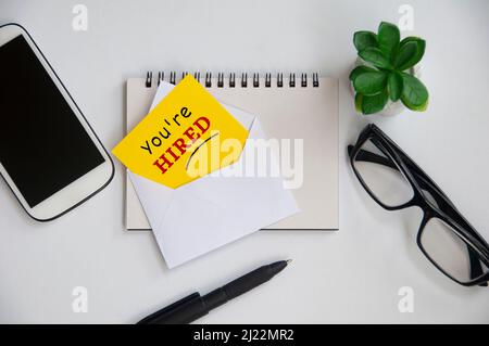 You are hired text on yellow notepad in an envelope. Employment concept Stock Photo