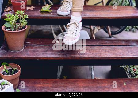 close-up front view detail foot on wooden staircase outdoors, with plants decorating the stairs. Stock Photo