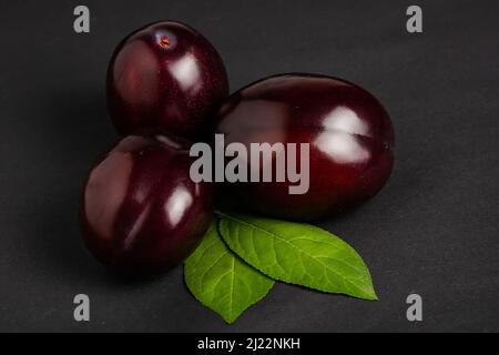 Plums with plum leaves on a dark background Stock Photo