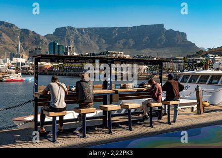 Cape Town South Africa. 2022.  Young men using the free wifi and mobile phone charging point on the waterfront in Cape Town South Africa. Stock Photo