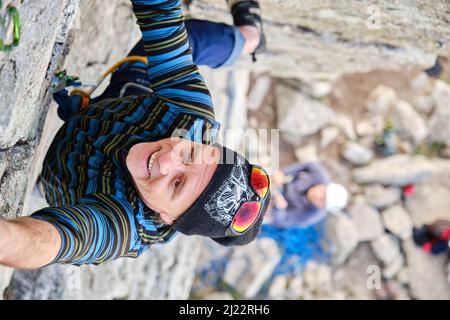 A Happy mature climber hanging on cliff Stock Photo