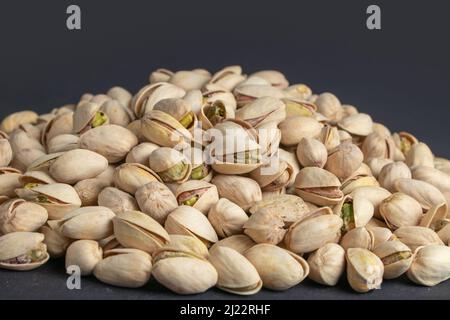 Pile of pistachios in the peel close-up on a dark background Stock Photo
