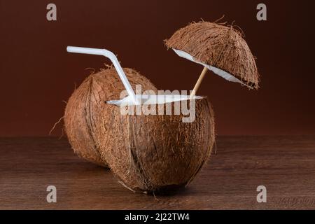 Coconut cocktail with a straw on brown background Stock Photo