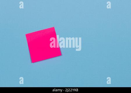 red adhesive paper note stuck to a blue background. Stock Photo