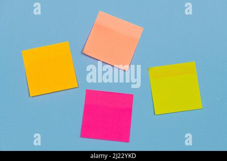 Coloured adhesive paper notes stuck to a blue background. Stock Photo