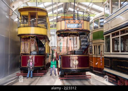 Derbyshire, UK – 5 April 2018: Two children pose before the vintage trams stored in the vehicle garage at Crich Tramway Village Stock Photo