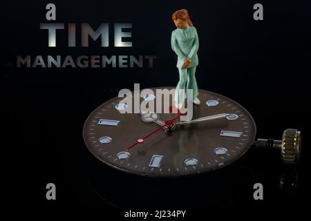 Businesswoman standing on watch under time pressure. Time management concept. Stock Photo