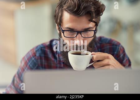 Hes the special combination of artistic, creative, and technically inclined. Shot of a designer having coffee while working on his laptop. Stock Photo
