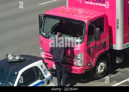 A traffic agent tickets a moving van in the Chelsea neighborhood of New York on Tuesday, March 22, 2022. (© Richard B. Levine) Stock Photo