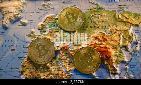 Gold metal bitcoin coins on a 3D relief world map. Stock Photo