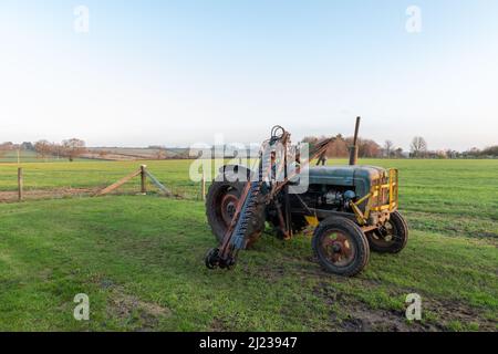 An old antique hedge trimmer mounted on a vintage tractor Stock Photo