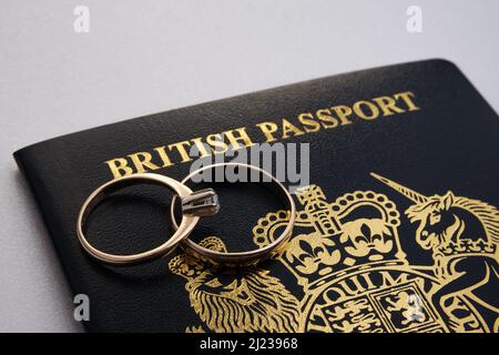 Gold rings on top of a new dark blue British passport. Concept for UK Fiance visa or Spouse Visa. Stafford, United Kingdom, March 29, 2022. Stock Photo