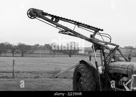 An old antique hedge trimmer mounted on a vintage tractor Stock Photo