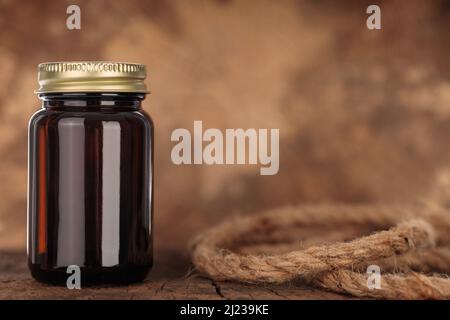 Empty mock-up of medical bottle for tablets. Transparent amber glass bottle on wooden background. Concept of herbal medicine. Stock Photo