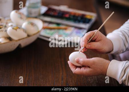 Woman painting a water colors on fantasy chicken eggs for Easter egg festival. Female drawing little yellow chick. The symbolic of Spring. Easter Stock Photo