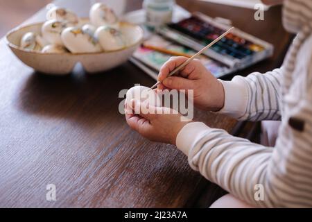 Woman painting a water colors on fantasy chicken eggs for Easter egg festival. Female drawing little yellow chick. The symbolic of Spring. Easter Stock Photo
