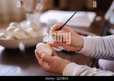Woman painting a water colors on fantasy chicken eggs for Easter egg festival. Female drawing little yellow chick. The symbolic of Spring. Easter Stock Photo