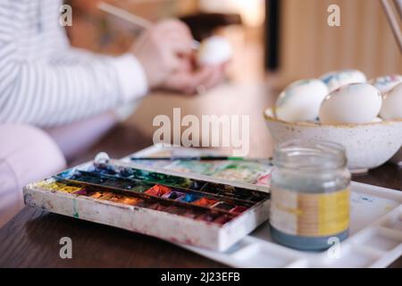 Process of woman paiting a water colors on fantasy chicken eggs. Female preparing for Easter egg festival Stock Photo