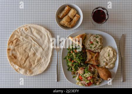 Top view of a plate of Lebanese specialties a pita bread and a bowl of pastries Stock Photo