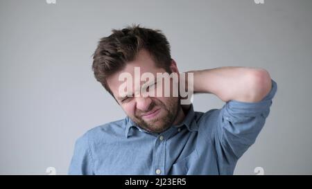 Handsome caucasian man having neck pain because of osteochondrosis. Studio shot Stock Photo