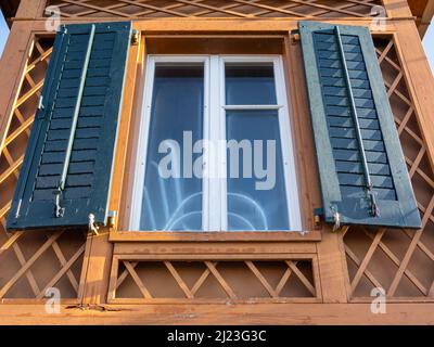 Zug, Switzerland - December 31, 2021: A window with blue shutters on small garden cottage with special wooden details from Switzerland Stock Photo