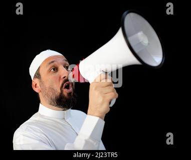 Muslim pilgrim in white traditional clothes, saying message on megaphone. High quality photo Stock Photo