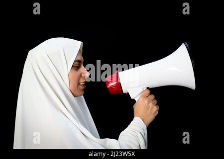 Muslim female pilgrim in white traditional clothes, saying message on megaphone. High quality photo Stock Photo