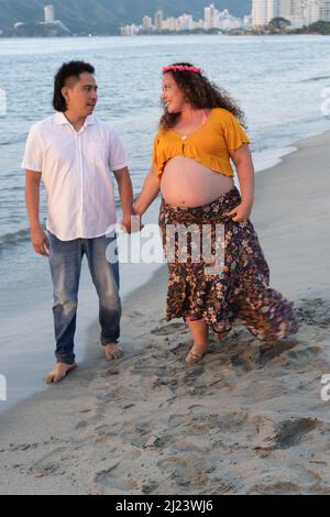 Pregnant couple walking on beach Stock Photo