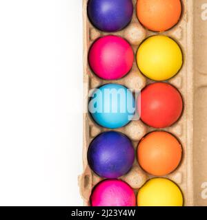 Colored easter eggs in brown carton on white background Stock Photo