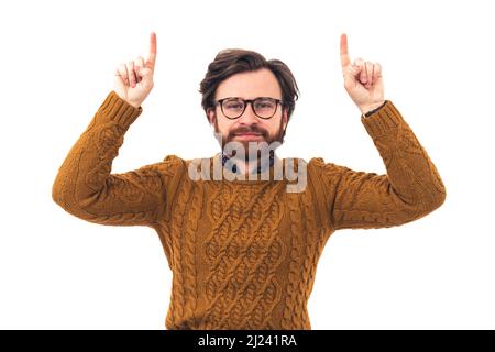 Young handsome Caucasian man with glasses keeping his hands up, pointing at something above him brown knitted sweater portrait isolated copy space white background . High quality photo Stock Photo