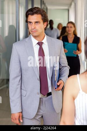 Businessman walking along office corridor Stock Photo