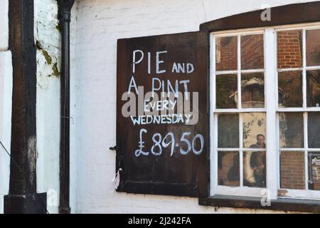 A cheeky pub food sign reflecting rising cost of living; at the Olde George, Shoreham, Kent, UK now being renovated. Close to the Mount Vineyard. Stock Photo