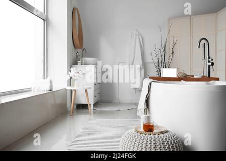 Tray with tablet computer and massage brush on bathtub in room Stock Photo