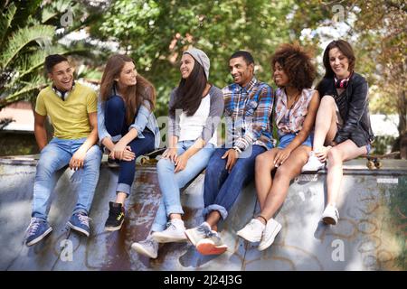 What are we gonna do this summer. Shot of a group of young friends hanging out at a skate park. Stock Photo