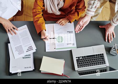 Above view of group of economists discussing financial documents with data at meeting while businessman explaining statistics Stock Photo