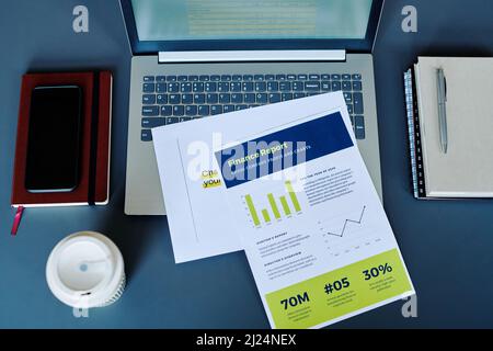 Overview of financial papers on laptop keyboard surrounded by office supplies on workplace of modern economist or auditor Stock Photo