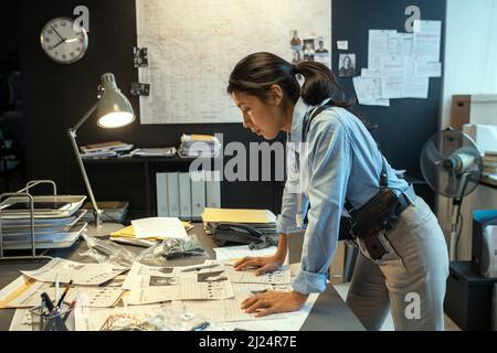 Side view of young serious female detective learning personal information of criminal authority or leader of gang Stock Photo