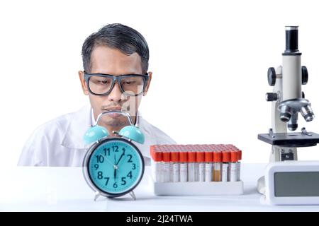 Asian nerd scientist with a microscope and medical tube rack on the desk isolated over white background Stock Photo