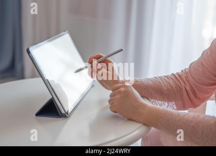 female artist using smart stylus for drawing picture on tablet touch screen device, working home. Cropped view of woman using digital tablet with elec Stock Photo
