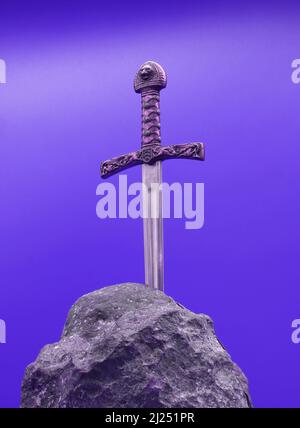 Excalibur, the mythical sword in the stone of King Arthur on purple background Stock Photo