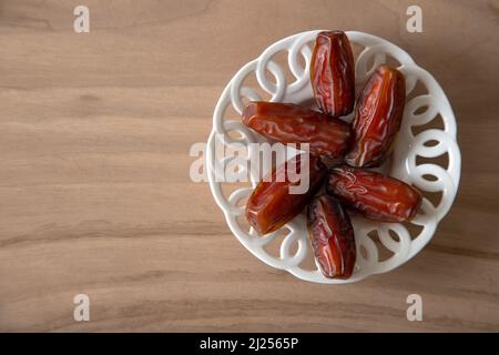 Date fruit in bowl on wooden background, top view Stock Photo