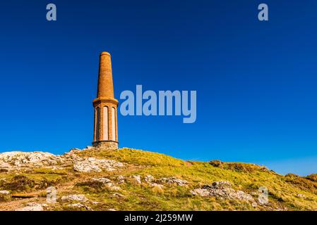 The Cape Cornwall Mine chimney against a deep blue sky at Cape Cornwall, near Land's End, Penzance, Cornwall, UK Stock Photo