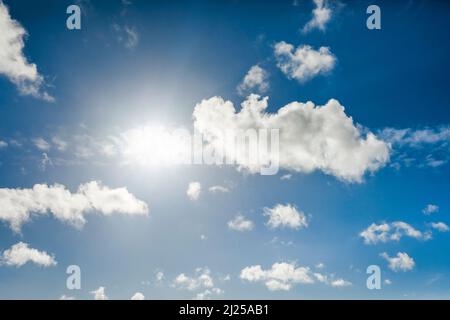 Sun backlights cumulus clouds in blue sky Stock Photo