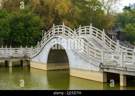 Chinese style pedestrian stone arch bridge over lake in park Stock Photo